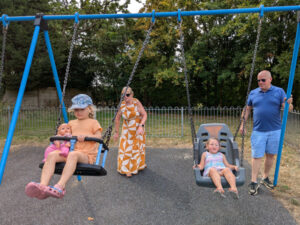 2 young girls enjoying being pushed on the new swings