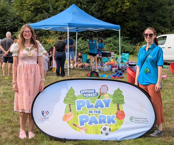 EFDC Chairman Louise Mead and one of EFDCs Community Development and Wellbeing team stand either side of a Play in the Park banner