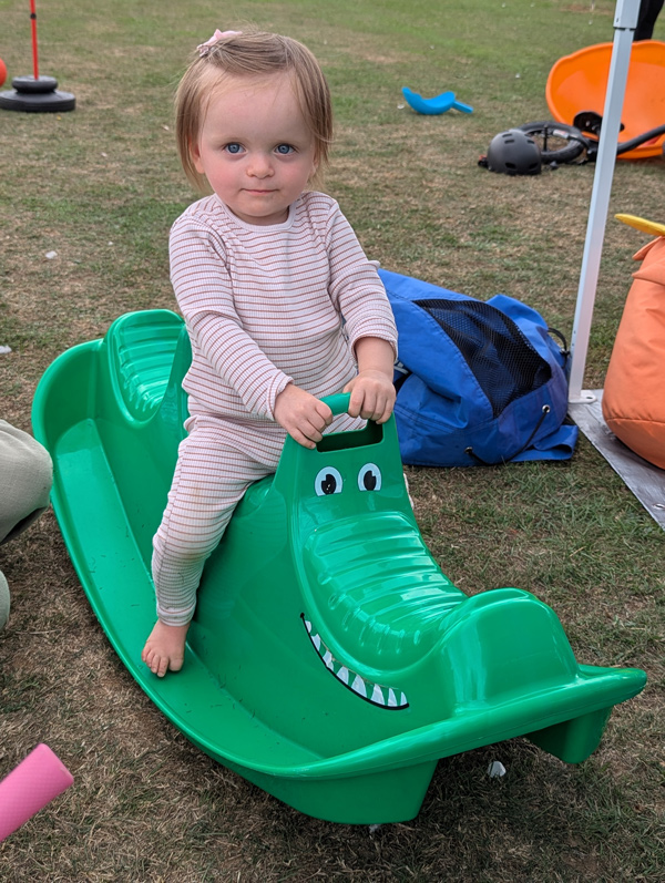 A toddler plays on a green crocodile rocker