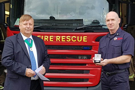 Bradley Reynolds receiving the Community Service medal for Essex Fire and Rescue from Cllr Richard Bassett