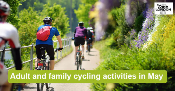 Group of cyclists riding single file along pathway surrounded by plants and flowers